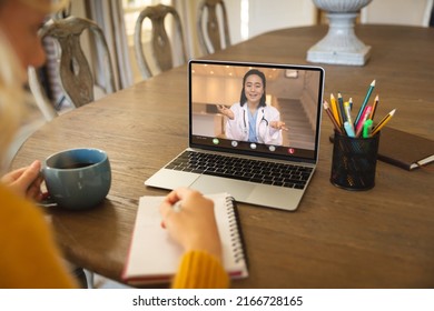 Asian female doctor gesturing during video call with caucasian businesswoman writing on diary. Unaltered, business, wireless technology, meeting, healthcare worker and office concept. - Shutterstock ID 2166728165