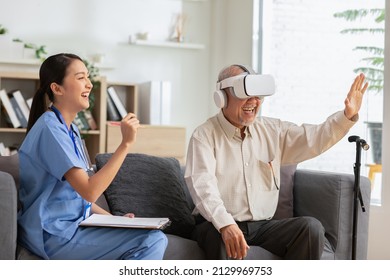 Asian Female Doctor Give Advice Elderly Patient Using VR Or Virtual Reality Glasses Headset Pointing Objects Or Touching Tracking Health.Happy Senior Man Having Fun With Goggle Using VR Enjoy At Home