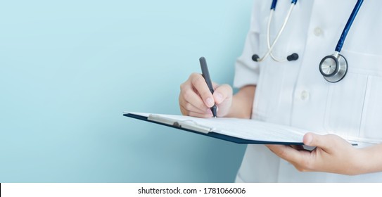 Asian Female Doctor Hand Taking Note Information Of Patient In Paperwork Checklist On Clipboard With  Blue Background, Isolated, Banner.