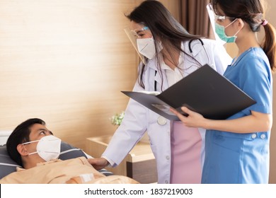 Asian Female Doctor And Nurse Wearing Mask Checking Health Of Senior Old Patient In Hospital Recovery Room. Woman Medic Checking Heart Rate Pulse And Giving Health Care Advisory.