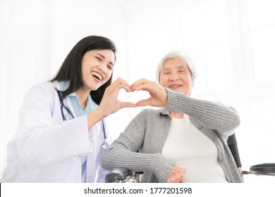 Asian Female Doctor And Old Patient Show Heart Sign With Hand, Happiness And Relationship In Hospital, They Feeling Happy And Smile On White Background