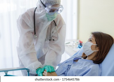 Asian Female Doctor In Protection Suit And A Mask Is Holding The Patient's Hand To Encourage. Concepts Of Care And Treatment For Patients With COVID 19.