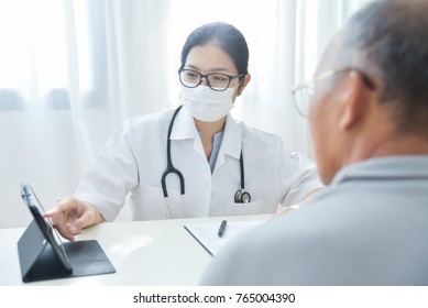 Asian Female Doctor with protective mask discussing with senior man patient about a chest radiograph in digital tablet computer in medical office. X-ray. BeH3althy - Shutterstock ID 765004390