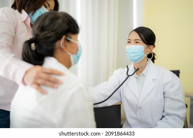 Asian Female Doctor Talking To An Elderly Woman To Maintain Health With A Smile, The Concept Is To Take Care Of Health, Elderly Patients, Teenage Doctors. Check Heartbeat Wearing A Mask