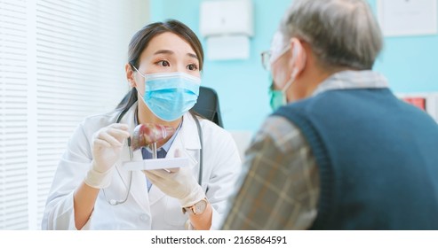 Asian Female Doctor Wearing Face Mask Is Showing Liver Model And Explaining To Elder Senior Man Patient In Hospital