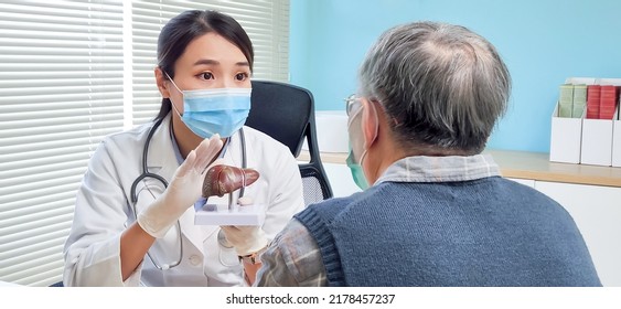 asian female doctor wearing face mask is showing liver model and explaining to elder senior man patient in hospital - Powered by Shutterstock