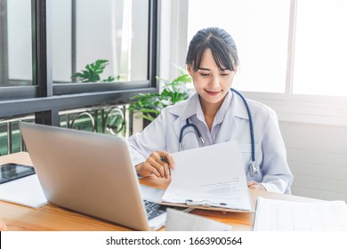 asian female doctor working in hospital office looking and reviewing documentation of forms and contracts of health care, health insurance, diagnosis of patients medical records, using laptop computer - Powered by Shutterstock