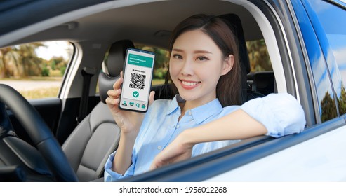 Asian Female Driver Shows Health Passport On Mobile Phone Which Indicates A Vaccination Against Covid-19 In Car