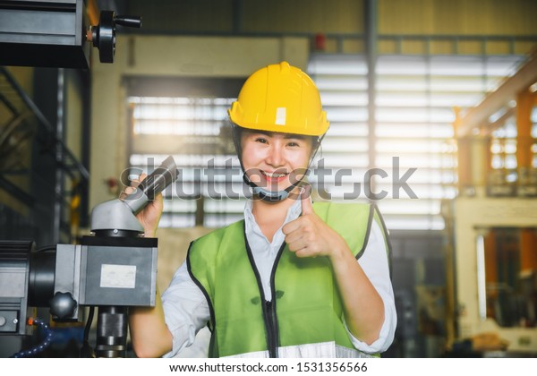  Asian female engineer factory inspection with robot\
ai machine assist production engineer in industry She wears a\
helmet female working metalwork control in industrial In a plastic\
factory for car