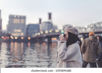 Asian female enjoying Willamette river sunset in downtown Portland, winter season