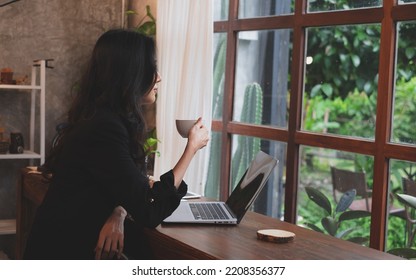 Asian Female Entrepreneur Or Businesswoman Having A Relaxing, Chilling, Creative Comfortable Moment While Drinking A Cup Of Coffee In The Morning Before Start Business. Concept Of Work From Home.