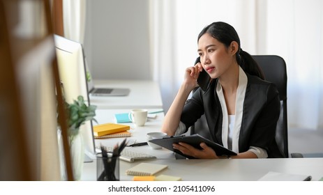 An Asian female entrepreneur is talking with her supplier on the phone. A businesswoman is calling her partner.