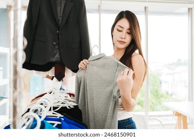 Asian female fashion designer or tailor checking finished clothes. final inspection before sending it to the customer. Dressmaker working and designing new collections in an atelier tailor workshop. - Powered by Shutterstock