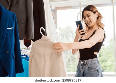 Asian female fashion designer or tailor checking finished clothes. final inspection before sending it to the customer. Dressmaker working and designing new collections in an atelier tailor workshop. - Powered by Shutterstock