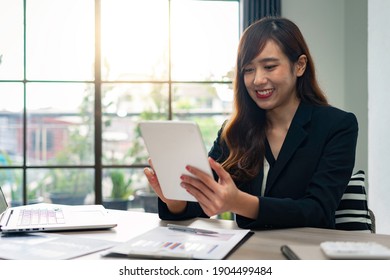 Asian Female Finance Worker Sitting At Work, Answering E-mails On The Tablet. At Home Office Table, Sit At Work With Happiness And Smile, Work From Home Ideas.