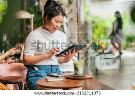 asian female freelance digital nomad career happiness workation cheerful smiling working online with smart device tablet smartphone abroad occupation project work anywhere new frameless lifestyle cafe