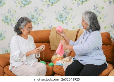 Asian female friends knitting on sofa at home, Senior women knitting together in living room - Powered by Shutterstock - Get 15% off with code: PIKWIZARD15