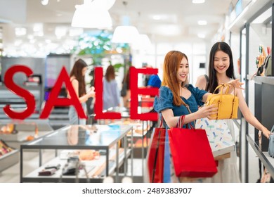 Asian female friends travel, relax, and shop together. Don't be happy. In a modern department store, Bangkok City drums to buy clothes and cosmetics together and holding a shopping paper bag in hand - Powered by Shutterstock