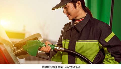 Asian Female Gas Station Employee Refueling Car