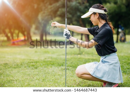 Asian female golfer look happy with her golf game.Professional female golfer holding golf club on field and looking away.
