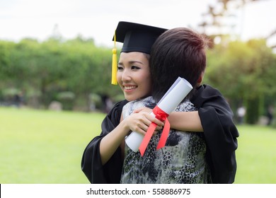 Asian female graduate student and family hug celebrating graduation
