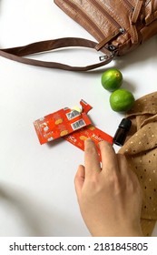 Asian Female Hand Taking Xonce Supplement Vitamin C Pill Or Tablet Beside Brown Leather Bag And Napkin On White Table Background Board High Key, Pasuruan, Indonesia, July - 2022