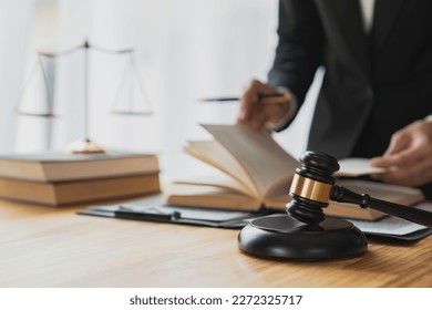 Asian female lawyer, law adviser, businessman looking through the law Business deal in the book working with the scales of the god of justice justice law concept. - Shutterstock ID 2272325717