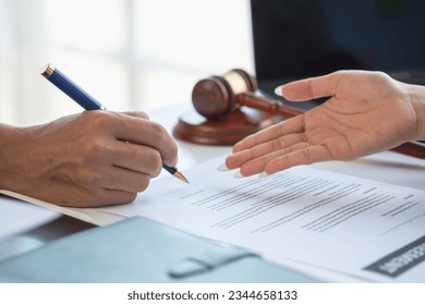 Asian female lawyer or legal advisor signing a contract The contract with the client on the desk in the law firm will guide the client as a legal counsel. - Shutterstock ID 2344658133