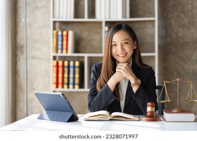 Asian female lawyer working in office or court With hammer and justice scales tablet on concept table online legal advice - Shutterstock ID 2328071997