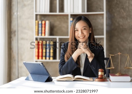 Asian female lawyer working in office or court With hammer and justice scales tablet on concept table online legal advice