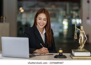 Asian Female Lawyer Working On Laptop Computer And Reading Law Books And Taking Note On Office Work Legal Service Concept.