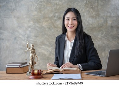 Asian Female Lawyer Working On Laptop Computer And Reading Law Books And Taking Note On Office Work Legal Service Concept.