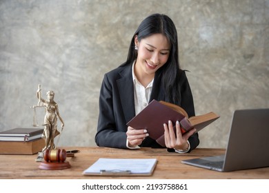 Asian Female Lawyer Working On Laptop Computer And Reading Law Books And Taking Note On Office Work Legal Service Concept.