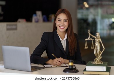 Asian Female Lawyer Working On Laptop Computer And Reading Law Books And Taking Note On Office Work Legal Service Concept.