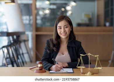 Asian Female Lawyer Working On Laptop Computer And Reading Law Books And Taking Note On Office Work Legal Service Concept.