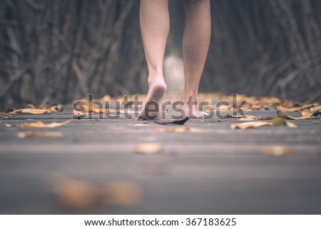Asian female legs walking towards on wooden bridge