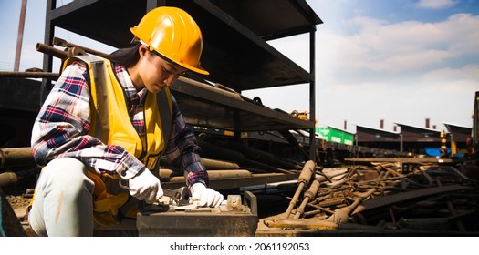 Asian Female Maintenance Worker Wearing A Helmet And Yellow Vest Is Holding A Wrench Working In Warehouse.