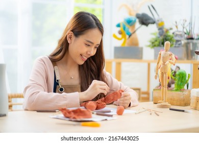 Asian Female making study from tablet streaming course online in apron costume for her hobby clay sculpture online course at home,asian casual lifestyle and hobby in holiday at home concept.