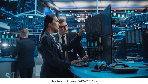 Asian Female and Male Stock Exchange Agents Using Computer, Discussing Investment Strategy for an International Business Client, Working in an Office Building Surrounded by Computer Screens - Powered by Shutterstock