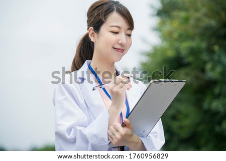Asian female medical worker in white coat with medical chart and pen