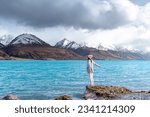 Asian female model enjoy the beautiful scenic sunrise view of Lake Pukaki east bank, with their mesmerizing turquoise hue and reflect the majestic snow-capped Southern Alps.