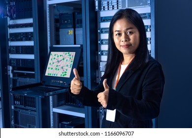 Asian Female Network Administrator Show Thumb Up Hands To Confirm Great Work And Trustworthy In Front Of Networking And Servers Rack Cabinet In Data Center Room