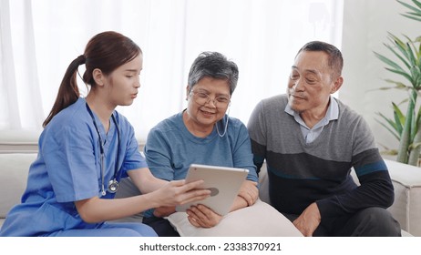 Asian female nurse caregiver is describing condition health of the elderly old couple on tablet. Homecare nursing service and elderly people health care. Elderly care concept - Powered by Shutterstock