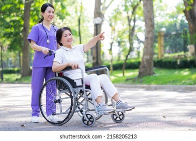 Asian Female Nurse Taking Care Of A Middle-aged Female Patient In The Park