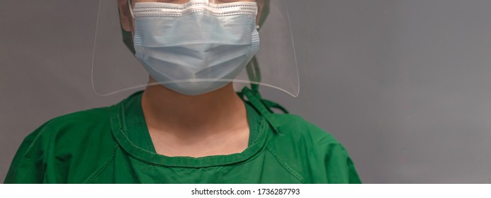 Asian Female Nurse Wears Surgical Masks, Green Gown, Face Shield, And A Stethoscope Around The Neck. Stand With Elegance And Confidence. Safeguarding Yourself Against The Coronavirus Concept.