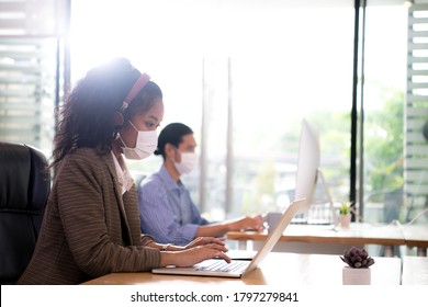 Asian Female Office Worker Wearing Face Mask Working In The New Normal Office And Doing Social Distancing During Coronavirus COVIC-19 Pandemic