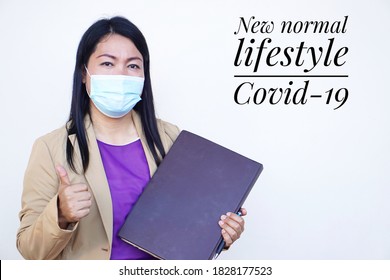 Asian Female Office Worker Wears Hygienic Mask On Her Face At Work To Protect From Coronavirus Or Covid-19. Concept For New Normal Lifestyle At Work. Awareness Of Wearing Facemask.Soft Focus