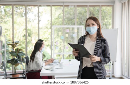 Asian female office worker wears hygienic mask on her face at work to protect from coronavirus or Covid-19. Concept for New normal lifestyle at work. Awareness of wearing facemask.Soft focus - Powered by Shutterstock