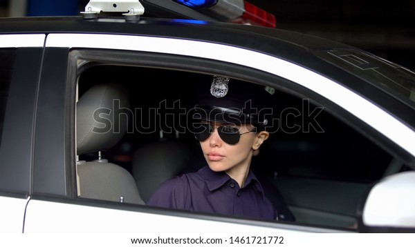 Asian female officer riding in car, monitoring\
traffic law and order in\
city