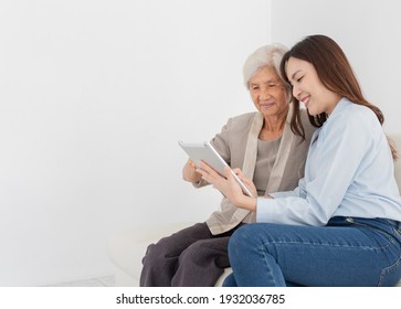 Asian Female And Old Female Search Information With Tablet Computer, They Feeling Happy And Smile, They Sitting On Sofa, Mother's Day And Happiness Family Time, Technology And Social Network